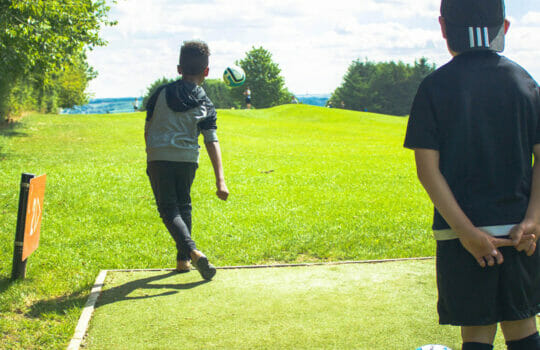 Child kicking a football at Footgolf