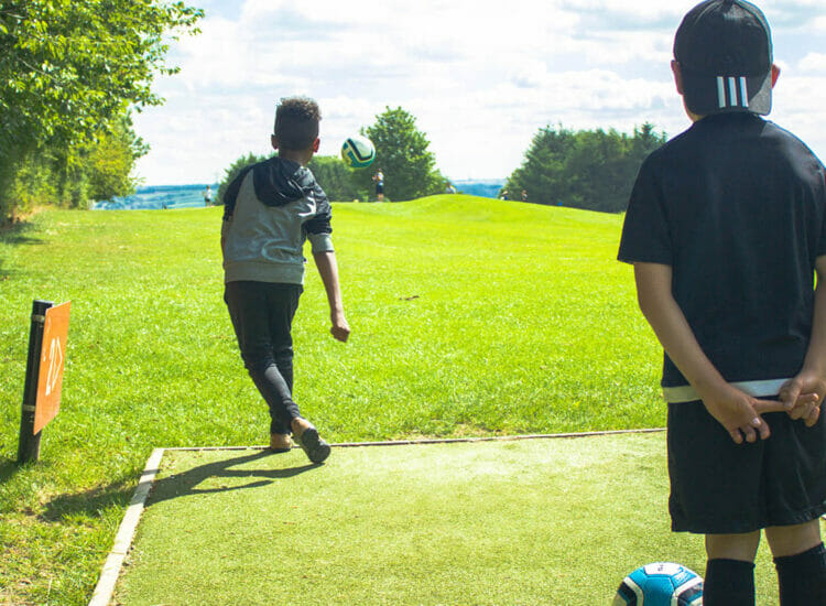 Child kicking a football at Footgolf